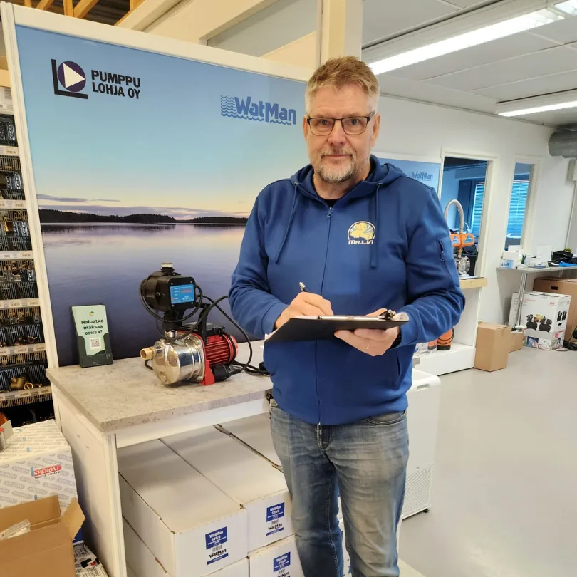 LVI-ammattilainen tarkastaa taskulampulla vanhan lämminvesivaraajan hapettuneita putkia ja varoventtiiliä.